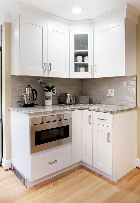 Corner cabinet area showing glass cabinet door front for showcasing valuables, and custom designed tote kick heater vent. Kitchen Corner Cabinet Upper, Small Corner Upper Cabinet, Small Corner Kitchen Layout, Glass Upper Cabinets Corner, Upper Corner Cabinet Pull Out, Fridge Cabinet Surround Corner, Upper Corner Kitchen Cabinet Glass, Coffee Corner Kitchen, Corner Kitchen Layout