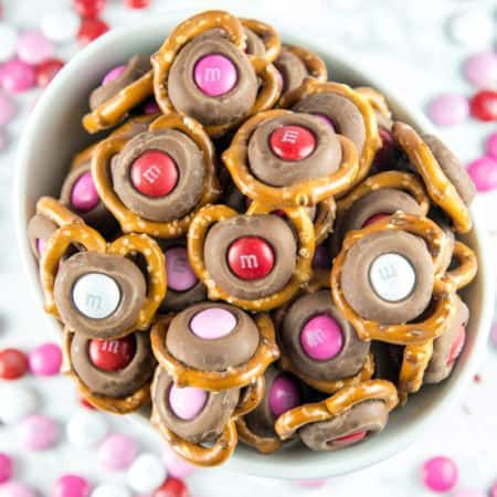 M&M Pretzel Kisses: a pretzel, a Hershey kiss, and a fun colored M&M -- so easy, but the bite-sized sweet and salty combination is irresistible. Match M&M colors to holidays for a fun school treat! #dessert #valentines Pretzel Hershey Kisses, Pretzel Kisses, Mint Chocolate Cheesecake, Hersheys Kisses, Vegetable Tart, Bunsen Burner, Fig Bars, Pinwheel Cookies, Chocolate Babka