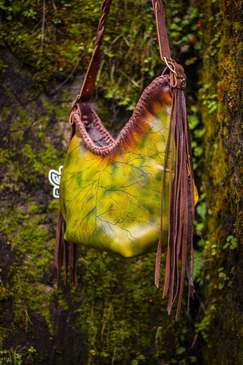 Artistic Detailing: The bag showcases 3D sculpted leaves and fern fronds, creating a stunning leaf texture that reflects a macro nature style. The intricate design features whimsical and organic elements, perfect for lovers of the woodland and faerie aesthetic. Color Palette: With rich green, brown, yellow, and orange tones, this bag evokes the beauty of a vibrant forest, making it a unique statement piece for any occasion. Braided and Fringed Accents: The bag is adorned with long fringe and int Faerie Aesthetic, Aesthetic Color Palette, Fern Frond, Organic Elements, Nature Style, Aesthetic Color, Leaf Texture, Long Fringe, Orange Tones