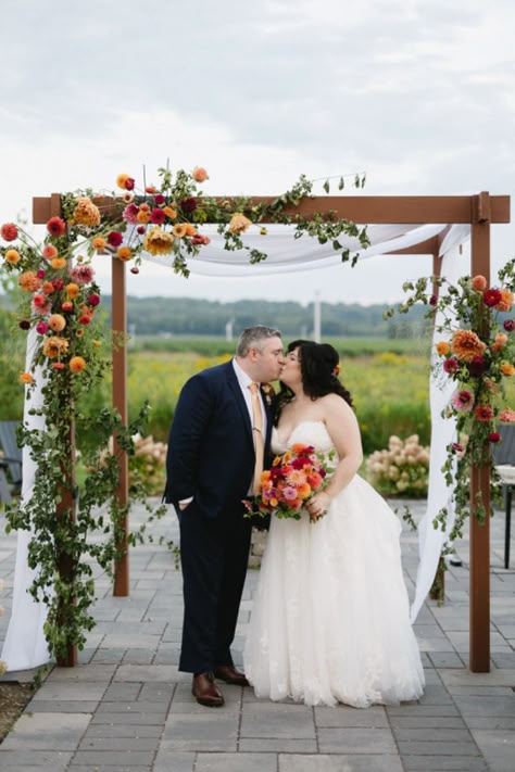 Handmade wood chuppah featuring ivory draping and colourful florals for a wedding ceremony set on a beautiful vineyard in Niagara-on-the-lake. Wood Wedding Arch With Flowers, Wedding Arbors Outdoor Ceremony Arch, Fall Chuppah Flowers, Wedding Ceremony Chuppah, Chuppah Flowers Simple, Communion Wedding Ceremony, Chuppah Simple, Colorful Chuppah, Chuppah Florals