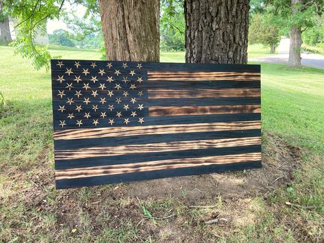 A beautiful wood burned flag sign that has carved stars and screw eyes with a metal hanging wire on the back. This flag has not been stained but just different degrees of burning to create the light and dark effects on the board. It would be a perfect Father's Day gift, Fourth of July gift or to hang in your man cave. A coat of polycrylic not only protects the wood but adds beauty as well. This Flag is meant for indoor use. *measurements are 32 x 60 inches For similar items click the links below American Flag Wood Burning, Burnt Wood Signs, Wood Flags Diy Projects, Flag Craft Ideas, American Flag Wood Projects, American Flag Room, Flag Diy Projects, Wooden Flags Diy, Wood American Flag Diy