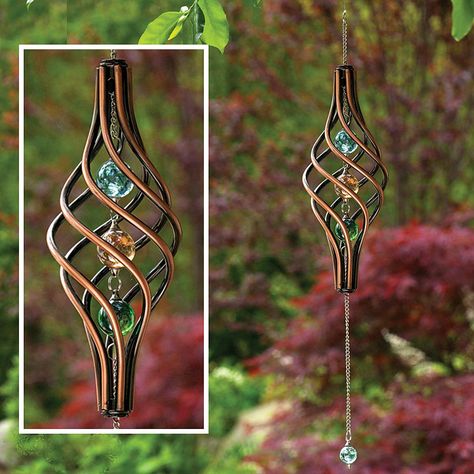 Watch this kinetic copper-finished wind sculpture as it gracefully spins in the wind. The twisted cage holds 3 iridescent marbles with 1 additional marble that swings from the metal chain for a stunning visual effect. 22" long, ready to hang. Copper Wind Spinners, Whimsy Garden, Wind Ornaments, Kinetic Wind Spinners, Upcycled Garden, Trees Garden, Garden Wind Spinners, Quilt Hangers, Bottle Trees