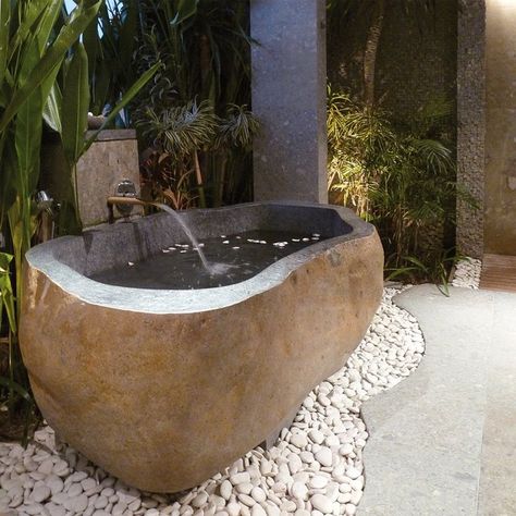 Huge river rock bathtub. Perfect to be placed outdoors, it is a natural bathtub that reminds of riverside stones with rounded edges. Sitting on a base made from small river stones, it is ideal for people who love being surrounded by nature. From the outside, it looks like a stone, but interiors with clean and sophisticated alcove tell the story of a modern bathtub. Made from rough beige granite, its outer surface nicely shows off intricate patterns of natural stone. Rock Bathtub, Bathroom Equipment, Bath Tube, Bath Surround, Balinese Garden, Cottage Interior Design, Marble Bathtub, Cream Marble, Modern Lake House