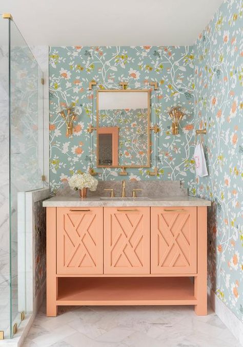 Beautiful blue and orange floral wallpaper covers the walls of this small bathroom boasting an orange sherbert washstand accented with brass hardware and a brass faucet kit fixed beneath a brass and lucite mirror flanked by brass sconces. Florida Bungalow, Peach Bathroom, Houston Interior Designers, Orange Bathrooms, Bathroom Color Schemes, Best Outdoor Furniture, Bathroom Color, Old Florida, Stylish Bathroom