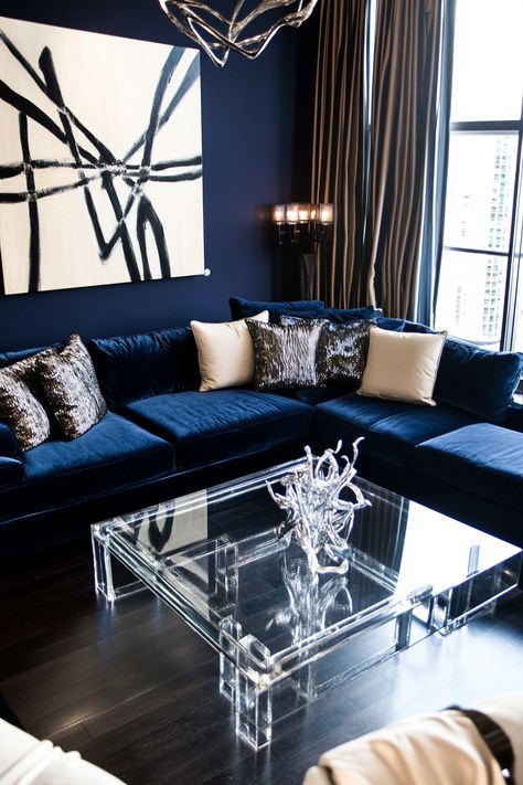 Transform your space with this chic living room decor. Featuring a velvet navy sofa, abstract art, and a sleek acrylic table, this setup blends luxury and contemporary style effortlessly. #LivingRoomDecor #ModernDesign #HomeInspo Living Room Decor Ideas Navy Blue, Blue Black Living Room Ideas, Living Room With Dark Blue Couch, Navy And Black Living Room, Blue And Silver Living Room Ideas, Navy Blue Sofa Living Room Ideas, Leather Sectional Decor, Navy Blue Living Room Ideas, Classy Apartment Decor