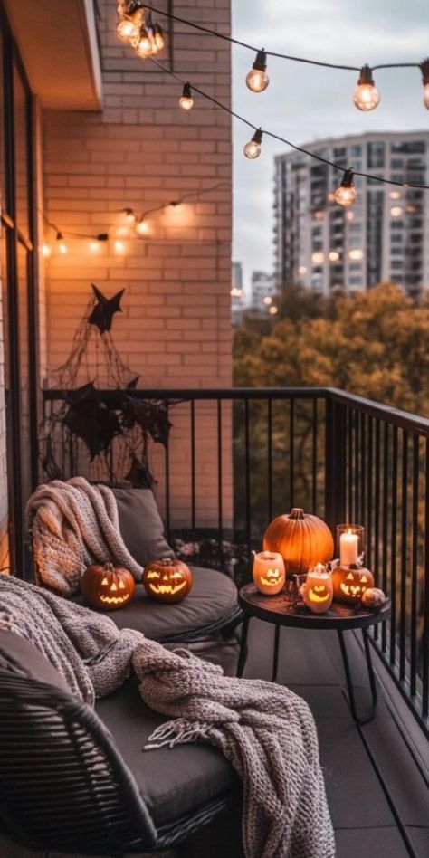 Cozy balcony decorated for Halloween with string lights, carved pumpkins, and blankets. Apartment Balcony Fall Decor, Apartment Decorating Halloween, Ugly Apartment Decorating Rental, Fall Apartment Patio Decor, Apartment Balcony Decor Ideas, Apartment Patio Halloween Decor, Halloween Apartment Decor Balcony, Apartment Porch Halloween Decorations, Cute Apartment Balcony