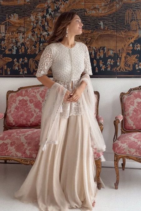 Buy Ivory Net Embroidery Thread Round Peplum Kurta Sharara Set For Women by SAISHA Online at Aza Fashions. Anarkali Sets With Pearl Embroidery In Cream, Cream Lace Work Sets For Reception, Elegant Floor-length Sharara For Ceremony, Anarkali Cream Sharara With Pearl Embroidery, Elegant Eid Peplum Set, Cream Anarkali Set With Lace Work, Elegant Peplum Set For Eid, Fitted Beige Lace Work Sets, Festive Off White Sets With Lace Work