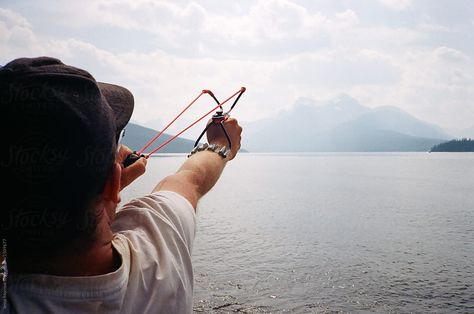 Young Man Shooting Sling Shot Wrist Rocket While Camping  #outdoors #people #adult #aggressive #aim #casual #catapult Wrist Rocket, Sling Shot, Camping Outdoors, Us Images, Archery, Rocket, Camping, Stock Photos, Quick Saves