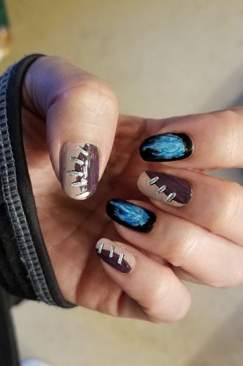 Nails painted to mimic Dabi's skin on thumb, middle and pinkie fingers.  Those nails are each  painted roughly in half with two colors, half a purplish hued light beige, the other half a dark muted purple with faint light fuchsia lines. Silver "staples" are painted across the centers of where the two contrasting colors meet. The pointer and ring fingers are painted as Dabi's blue flames.  They are painted with a black background with pale blue flames over them. My Hero Academia Nail Design, Anime Nails My Hero Academia, Dabi Inspired Nails, Dabi Nails Design, Mha Nail Ideas, Dabi Inspired Outfit, Mha Acrylic Nails, My Hero Nails, My Hero Academia Nail Art