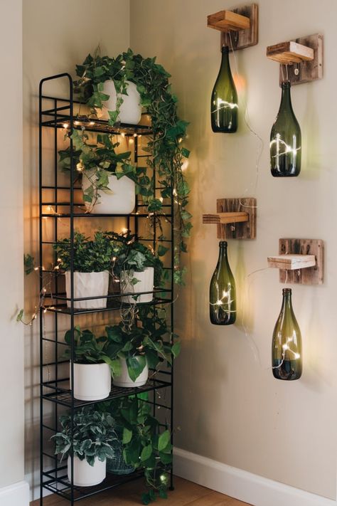 Transform your space into a cozy haven with a rustic plant shelf featuring cascading greenery and white pots. Fairy lights intertwined with plants and wine bottle lights mounted on wood panels add a warm and whimsical glow. Perfect for serene, nature-inspired interiors. #RusticPlantDecor #CozyCornerIdeas #FairyLightDesign #GreeneryDecor #ModernRusticStyle #IndoorPlants #WhimsicalInteriors #BottleLightCraft #HomeDecorGoals #PlantShelfStyling Airbnb Asthetic, Bottle Fairy Lights, Plant Interior, Led Bottle Light, Wine Bottle Lights, White Pots, Greenery Decor, Serene Nature, Inspired Interiors