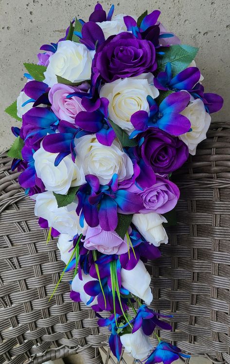 "This is a listing for a bridal bouquet made with high quality ivory, lavender and purple artificial roses, purple blue galaxy orchids and accented with leaves and greens.  Measures 11\" wide and cascades 18.5\"." Blue And Purple Cascading Bouquet, Cobalt Blue And Lavender Wedding, Royal Blue And Purple Wedding Dress, Galaxy Bouquet Bridal, Blue And Purple Orchid Bouquet, Purple Blue And White Bouquet, Galaxy Flower Arrangement, Deep Purple And Blue Wedding, Purple And Royal Blue Wedding Decor