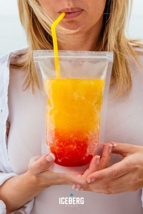 A woman holds a clear drink pouch filled with red and orange vodka slushie summer drink. Pouch Drinks Alcohol Recipes, Adult Capri Sun Recipe, Adult Capri Sun, Vodka Slushies, Best Vodka Cocktails, Mango Vodka, Vodka Sunrise, Frozen Drinks Alcohol, Mango And Pineapple