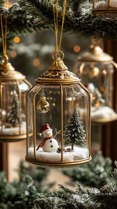 Festive glass terrarium ornaments with snowmen and trees hang from an evergreen tree, creating a magical winter wonderland. Home Decor Ornaments, Mini Glass Dome Ideas, How To Style Lanterns, Terrarium Christmas Ideas, Christmas Miniatures Diy, Christmas Terrariums, Miniature Christmas Decorations, House Party Decor, Miniature Christmas Ornaments