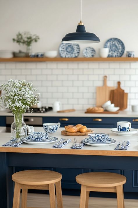 Elegant kitchen with blue accents, white subway tiles, and a table set for breakfast with patterned dishes and fresh flowers. Polish Pottery Inspired Kitchen, Blue White Wood Kitchen, Delft Blue Kitchen, Blue Willow Kitchen, French Blue Kitchen, White And Blue Kitchen, French Inspired Kitchen, White Wood Kitchens, Blue And White Kitchen