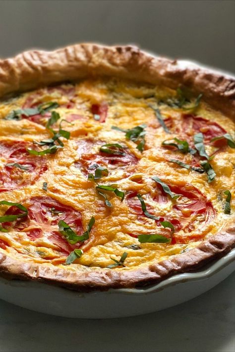 A quiche dish with round tomato slices laid in cheddar cheese and lightly topped with basil. Tomato Basil Mozzarella Quiche, Cheese And Tomato Quiche, Tomato Basil Quiche Recipes, Tomato Basil Tart Recipe, Quiche Recipes Savory, Freezable Quiche Recipes, Quiche Meal Ideas, Quiche Sundried Tomato, 3 Cheese Quiche 12 Tomatoes