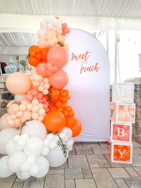 Baby shower peach themed balloon decor in the colours orange, coral, peach and white, with baby blocks beside it Peach Pink Orange Balloons, One Sweet Peach Balloon Garland, Pink And Orange Gender Reveal, Coral Balloon Arch, Peaches And Cream Baby Shower Ideas, One Sweet Peach Balloon Arch, One Sweet Peach Backdrop, Colourful Baby Shower Theme, Peachy Baby Shower Ideas