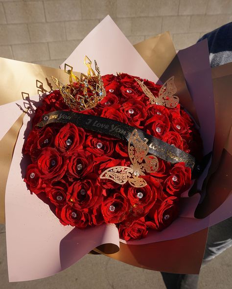 Unleash the passionate allure of love with our Royal Romance Bouquet. This luxurious arrangement boasts 50 velvety red roses, meticulously handpicked to express the depth of your affection. Each rose is lovingly nestled amongst an elegant ribbon emblazoned with “I Love You”, affirming your sentiments in a manner as timeless as love itself. Adorned with a regal crown and delicate butterflies, this bouquet transcends ordinary expressions of love, elevating your message into a grand gesture of romantic devotion. Red Roses Bouquet, Sweet Table Wedding, Black Red Wedding, Royal Romance, 12 Roses, Birthday Things, Dance Photo Shoot, Luxury Flower Bouquets, Matric Dance