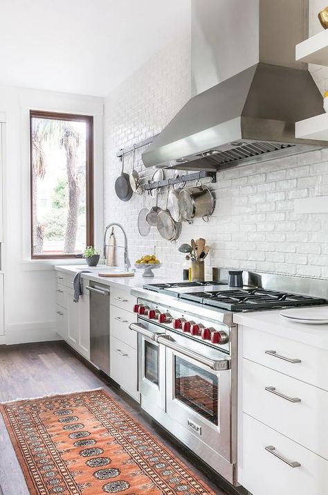 Who doesn't love upgrades? This gorgeous white kitchen features plenty starting with a Wolf dual range oven and stove, stainless steel vent hood and a dishwasher next to the white porcelain sink with a stainless steel pull out faucet. Painted Brick Backsplash, White Brick Backsplash, Exposed Brick Kitchen, Gorgeous White Kitchen, Brick Kitchen, Brick Backsplash, Farmhouse Kitchen Design, Kitchen Stove, White Brick