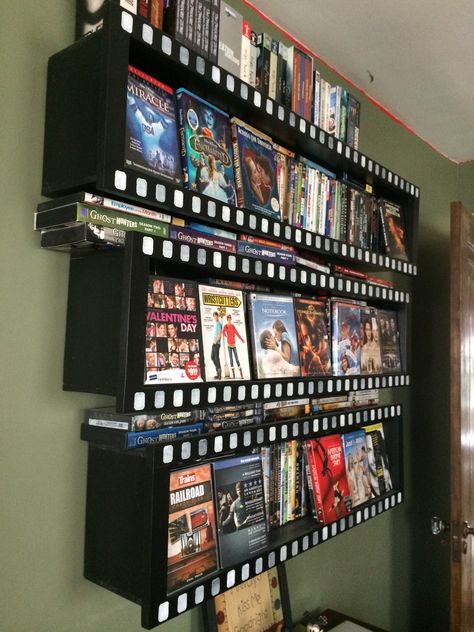 Home made wall-mounted DVD storage.  Painted black.  The 1x2 face trim is stamped with white squares to roughly replicate the little holes on a filmstrip.  Holds about 370-380 standard DVDs Movie Display Ideas, Dvd Storage Aesthetic, Movie Storage Ideas, Vhs Storage Ideas, Dvd Display Ideas, Movie Collection Display, Dvd Wall Storage, Bluray Storage, Diy Dvd Shelves