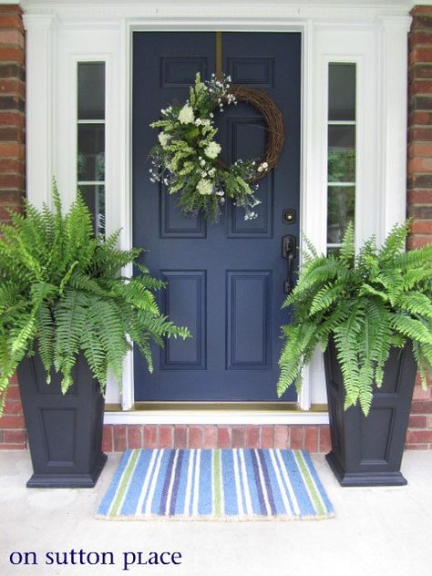 Trim all one color, allows the door color to pop!  Pretty wrath and bold statement made with flower boxes & boston fern. Navy Front Door, Blue Front Door, Red Brick House, Best Paint Colors, Front Door Colors, Front Porch Decorating, Exterior Paint Colors, Blue Door, Door Color