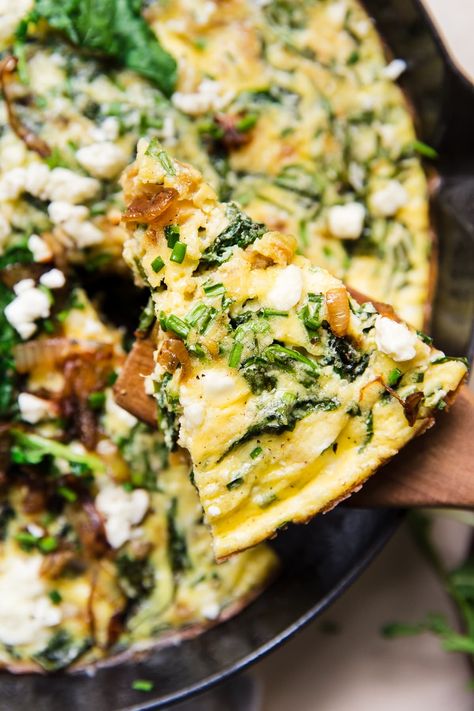 A silky pour of heavy cream helps this vegetable-laden frittata stay tender, light and bouncy, even as we load it up with rich caramelized onions, tangy feta and a veritable garden of baby kale. Caramelized Onion Frittata, Onion And Arugula Frittata, Carmelized Onion Frittata, French Onion Frittata, Frittata Photography, Gouda Frittata, Healthy Frittata Recipes, Breakfast Frittata Recipes, Arugula Frittata