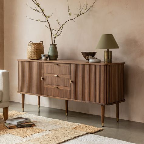 Our mid-century inspired Byron Sideboard is a vintage-style storage and display unit ideal for dining rooms and living spaces. Its warm walnut finish brings a timeless vintage look to your home, with two tambour slatted doors that slide open smoothly to the side, revealing adjustable glass shelving within. The sideboard features three central drawers, and is decorated with solid T-bar brass handles that match the gorgeous brass caps on the tapered legs. Our Byron collection also includes an extendable dining table, media unit, coffee table and side table. | Byron Sideboard by Atkin and Thyme, W160 x H75 cm Side Units Living Rooms, Side Boards And Buffets Living Room, Dining Room Sideboard Decor Ideas, Lounge Dining Room Ideas, Vintage And Modern Decor Mixing, Dining Room Sideboard Styling, Sideboard Decor Ideas, Art Deco Buffet Sideboard, Sideboard Decor Dining Room