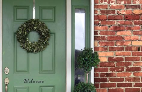 Front Door Colors for Brick Houses | Top Front Door Color Choices. Green front door with a wreath. red brick house, white trim. Gold hardware. green porch plants. House Front Door Colors, Brick House Front Door, Red Brick Homes, Brick House Front Door Colors, House Doors Colors, Orange Brick Houses, Brown Brick Houses, Brick House Colors, Green Front Door