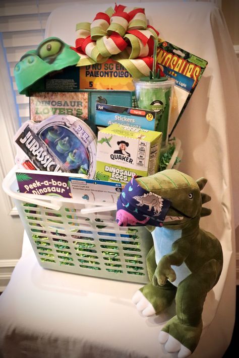 Perfect gift for the kid who LOVES Dinosaurs! This basket is filled with some unique finds including a paleontology kit with 5 activities, a dinosaur lover's cookie making kit, Jurassic Park Pez set collectors tin, oat-a-sauraus cereal, magic grow foam dinosaurs, foam dino hat, foam craft kit, stickers, tumbler filed with lime scented bath bombs & pouf, dinosaur night light, and a kid sized dino print face mask on a stuffed dinosaur. Dinosaur Gift Basket, Dino Hat, Dinosaur Night Light, Stuffed Dinosaur, Auction Basket, Auction Baskets, Dino Print, Cookie Making, Dinosaur Gifts