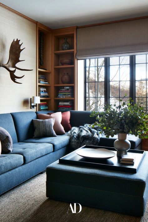 The star of the study is the seating: a denim-hued custom flannel sectional and a matching ottoman. As for the art, the designer decided to go for Alaskan moose antlers from Bucktails Taxidermy. Built-in wooden shelves store books and vases for added detail. The deep blue and tan hues of the space are consistent with the rest of the home. #livingroom #familyroom #library #den #mountains #aspen #colorado #skilodge #cabin #contemporary #ottoman #cozy #sofa #coffeetable #vases #windows #coffeetable White Oak Table, Sitting Nook, Modern Farmhouse Living Room Decor, Aspen Mountain, Farmhouse Living Room Decor Ideas, Mountain Chalet, Wine Tasting Room, Modern Farmhouse Living Room, Ski Chalet