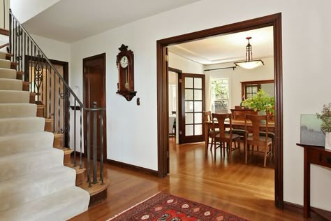 The foyer reveals a staircase and a formal dining room. White walls with wood trim. Yes. Walnut Trim Interior Modern, Mahogany Trim Living Room, Dark Wood Baseboards And Trim, Dining Room White Walls, White Walls With Wood Trim, Walls With Wood Trim, Painted Wood Trim, Mahogany Trim, Dining Room White