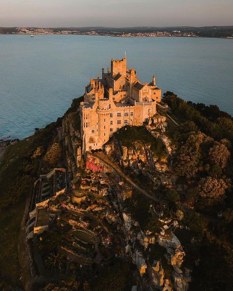 St Michael's Mount in Cornwall, UK. Historically, it is a Cornish counterpart of Mont-Saint-Michel in Normandy, France. The monastery founded by the Benedictines in the 12th century occupies the whole of the tidal island. You can reach it only at low tide, walking along a paved stone path running on the bottom of the bay. The ancient castle on top has since the mid-1600s been home to the St Aubyn family, who still live here today. Mount Saint Michel, Ancient Castle, St Michael's Mount, Cornwall Uk, Stone Path, Saint Michael, Normandy France, Random Ideas, 12th Century