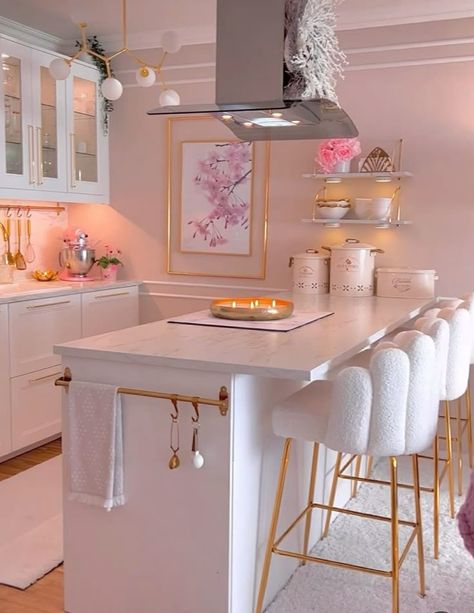 A beautifully designed kitchen featuring white cabinets, gold accents, pink decor, and plush white bar stools. White Kitchen With Gold And Pink Accents, Pink Accents Kitchen, Luxurious Apartment Kitchen, Pink And Gold House Decor, White And Pink House Interior, Cute Apartment Ideas Kitchen, Glam Kitchen Decor Apartment, Gold House Decor Interior Design, Cute Girly Apartment Decor