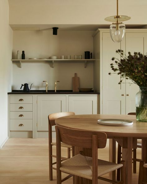 Kitchenette with green toned paint, simple wooden table and chairs, pretty pendant light, and some open shelving. British Standard Kitchen, Plain English Kitchen, Room Divider Headboard, Small Dining Area, Rural Retreats, Getaway Cabins, Luxury Cabin, Small Dining, World Of Interiors