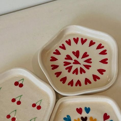 Cerameeq • Ceramics | Home & Lifestyle on Instagram: "New in! 💖✨ Adorable mini heart trays, cherry-tray 🍒, and vibrant multi-colored heart trays – perfect for adding charm to your decor or gifting a little love! 💌   #MiniHeartTray #CherryLove #ColorfulHearts #CuteDecor #HandmadeWithLove #GiftIdeas #AestheticVibes #TrendyDecor #HeartShaped #QuirkyAccessories #DIYDecor #HomeStyling #SmallBusinessLove #UniqueGifts #DecorGoals" Cute Trinket Tray, Trinket Tray Painting Ideas, Valentines Day Ceramics, Trinket Dish Painting Ideas, Dish Painting Ideas, Jewelry Dish Clay, Dish Painting, Oval Trinket Tray, Clay Trays