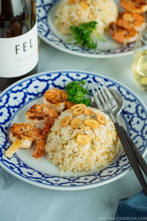 A blue and white plate containing Japanese Garlic Fried Rice topped with garlic chips and grilled shrimp skewer. Served with a glass of wine. Japanese Garlic Fried Rice Recipe, Okinawan Recipes, Yakimeshi Recipe, Japanese Cookbook, Chef Taro, Japanese Rice Dishes, Japanese Meals, Garlic Chips, Garlic Fried Rice