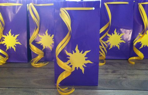 So pleased with the look of these bags!  My talented hubby drew up the sun symbol and whipped up these stickers for me. I slapped them on these purple paper bags, hole punched the tops, and tied them closed with golden Rapunzel hair....I mean curling ribbon.  Perfect!! Rapunzel Birthday Cake, Goodie Bag Ideas, Tangled Lanterns, Tangled Birthday Party, Rapunzel Birthday, Birthday Cake Writing, Rapunzel Birthday Party, Tangled Birthday, Rapunzel Party