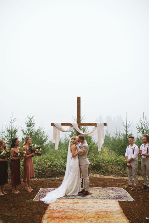 We built this cross using 12ft 2x4 and 6ft 2x4. I stained it with “Early American” wood stain and then we cemented it into the ground. The fabric is from Jo~Anne’s fabric. Wedding Cross With Drape, Diy Wooden Cross Wedding, Bride On Right Side Of Alter, Cross For Outdoor Wedding, Cross For Wedding Ceremony Altars, Wooden Cross Wedding Backdrop, Christian Wedding Ideas Decor Receptions, Country Wedding Altar, Wedding Wooden Cross