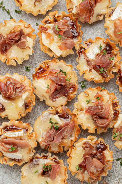 My Mini Brie Bites are an easy to make appetizer featuring creamy, melty brie, a rich, fruity fig jam, and crispy prosciutto all tucked in a flaky phyllo pastry shell. They are sweet & savory, can be made in advance, and are a crowd-pleasing appetizer every time! #briebites #brie #briecheese #brieappetizer #appetizers #appetizerideas #holidayappetizer Bacon Fig Appetizer, Brie Bite Appetizer Recipes, Brie Fig Prosciutto Puff Pastry, Puff Pastry Bites Savory, Mini Brie Puff Pastry Bites, Wonton Brie Appetizers, Brie And Prosciutto Puff Pastry, Mini Baked Brie Bites, Brie And Phyllo Appetizer