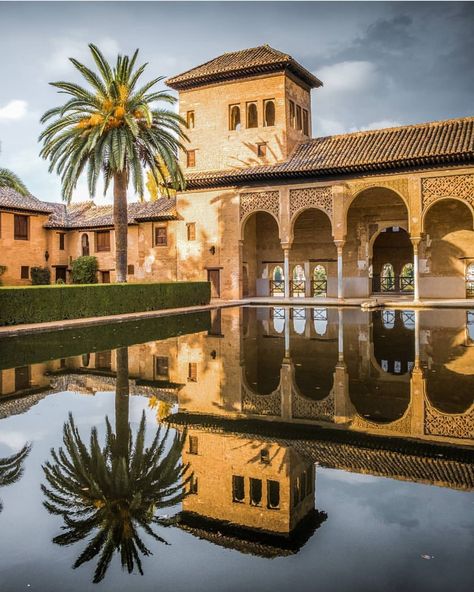 Palacio del Partal, Alhambra, Granada, Spain 🇪🇸 A serene view of the Palacio del Partal, one of the oldest structures within the Alhambra in Granada. The reflection of the tower, arches, and a tall palm tree in the tranquil waters of the pond creates a stunningly symmetrical image, emphasizing the elegance of Islamic architecture. The intricate stonework and lush gardens surrounding the palace enhance its timeless beauty, showcasing the Moorish influence that characterizes the Alhambra. This... Cheap Flights To Europe, Red Aesthetics, Alhambra Granada, Cheap Airfare, Best Vacation Destinations, Cities In Italy, Granada Spain, Trip To Europe, Islamic Architecture