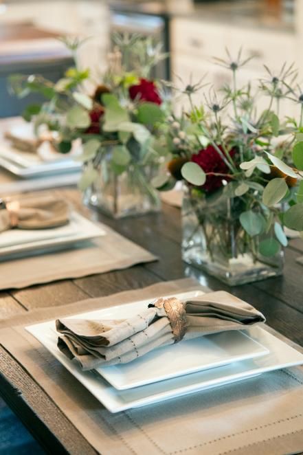 The+dining+table+is+set+with+neutral+toned+napkins+and+modern,+white+square+plates.+Low+vases+with+native+floral+arrangements+suit+the+homeowner's+youthful+tastes,+as+seen+on+HGTV's+Fixer+Upper.+ Craftsman Remodel, Magnolia Fixer Upper, Table Settings Everyday, Joanna Gaines Style, Hgtv Fixer Upper, Fall Flower Arrangements, Flower Arrangements Simple, Square Plate, Fixer Upper Style