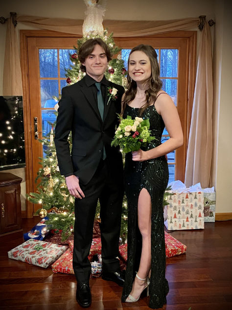 A young couple wearing formalwear posing in front of a Christmas tree Black Suit With Green Tie, Black Suit Green Tie, Suit With Green Tie, Men's Black Suit, Formal Inspiration, Forest Green Dresses, Prom Suit, Black Suit Men, Christmas Suit