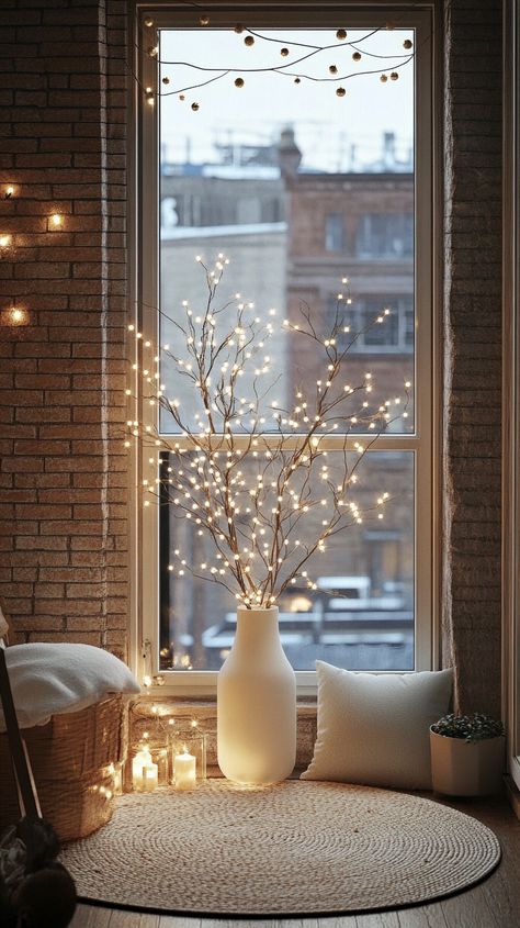 Minimalist Christmas decor featuring a white vase with branches, soft lighting, and a cityscape view through an open window. Decorating With Lights Indoors, Lighted Branches Decor, January Decor Ideas, Minimalistic Christmas Decor, January Decorating Ideas, Non Christmas Winter Decor, Fairy Light Decor, Audrey Core, Minimalist Christmas Decor Ideas