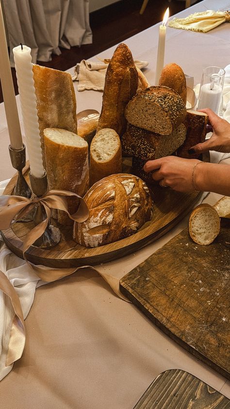 A beautifully simple holiday table featuring fresh, artisanal bread as an edible centerpiece. Paired with elegant candles and flowers, it creates a warm, inviting, and effortlessly festive look. Bread Wedding Centerpieces, Communion Bread And Wine, Bread Centerpiece, Wine Table Decor, Bread Table, Artisanal Bread, Bread And Wine, Edible Centerpieces, Candles And Flowers