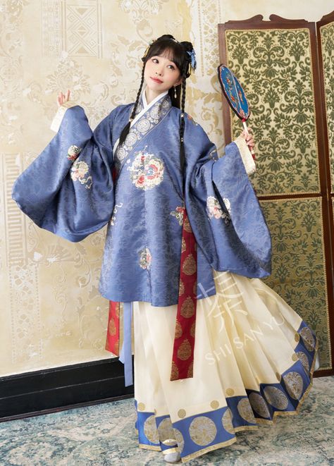 Experience the regal aesthetics of the Ming Dynasty with our high-density brocade Huangjia Huizhang 皇家徽章 Royal Emblem Set! Available in two exquisite colors, Spring Green and Navy Blue, this ensemble captures the essence of Ming fashions with a modern twist. The star of the show is the Jiaoling Ao 交领袄 (cross collar top), featuring the iconic Pipaxiu 琵琶袖 or "lute sleeves". These sleeves have a wide dip and curve in at the wrist to create an elegant bell shaped sleeve. Embellished with intricate c Hanfu Ming Dynasty, Ming Dynasty Clothing For Women, Han Dynasty Hanfu, Tang Dynasty Fashion, Ming Hanfu, Modern Chinese Fashion, Ming Dynasty Clothing, Royal Emblem, Ming Dynasty Hanfu