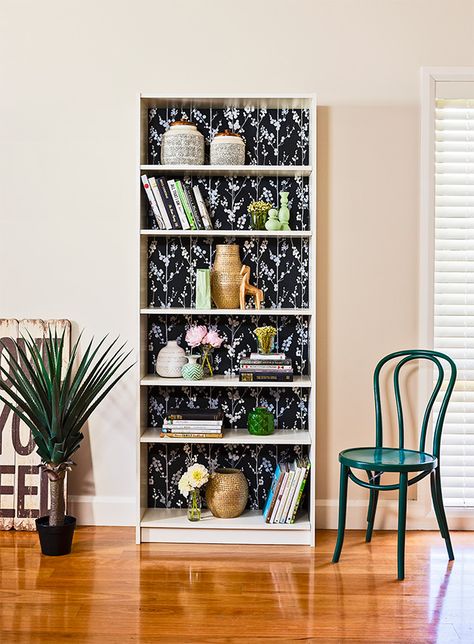 It's so easy to refresh a tired-looking bookcase by applying a wallpaper backing. Here's how it's done... Wallpaper Backed Shelves, Painted Bookcase With Wallpaper, Bookcase Makeover Wallpaper, Bookcase Backing Ideas, Painted Bookshelf With Wallpaper, Using Wallpaper On Furniture Bookshelves, Wallpaper Backed Bookcases, Wallpaper Bookcase Back, Bookshelves With Wallpaper Backing