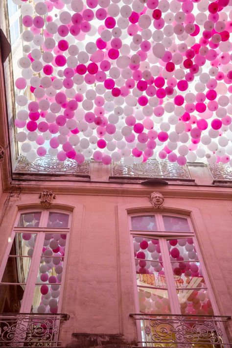 A Ceiling of Pink Balloons Contained in a French Hotel Courtyard Mimics the Fall of Cherry Blossoms | Colossal Balloon And Flower Backdrop, Red Art Painting, Ambient Advertising, Bts Party, Expo Dubai, Event Design Ideas, Flowering Cherry Tree, Balloon Installation, Colossal Art