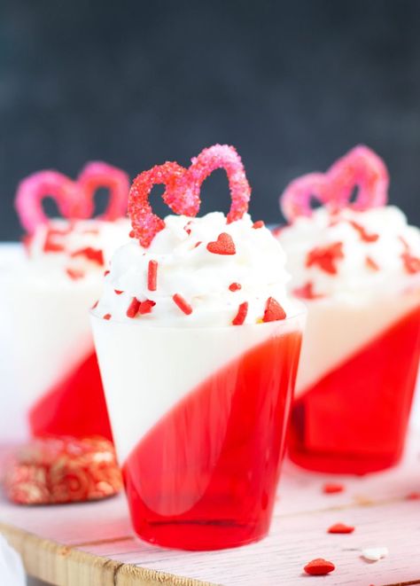 These Strawberries and Cream Layered Jell-O shots are a festive Valentine's Day treat with whipped cream vodka.  A heart made out of melted white chocolate and sugar sprinkles makes the perfect topper. Strawberry Cream Jello Shots, Red And White Jello Shots, Valentines Day Jello Shots, Canada Day Jello Shots, Valentine’s Day Jello Shots, Valentine Jello Shots, Valentine’s Day Shots, Valentines Shots, White Jello Shots