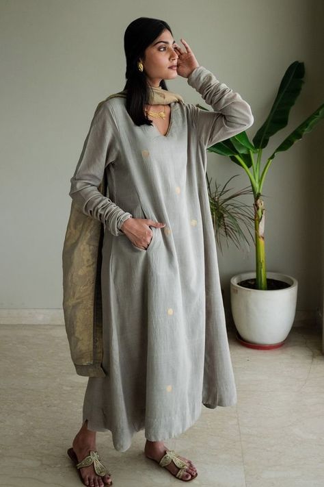 Taupe full sleeve kurta with coin sized gold bootas woven motifs. Paired with pant.
Components: 2
Pattern: Woven
Type Of Work: Bootas
Neckline: V neck
Sleeve Type: Churidar sleeves
Fabric: Kurta: Jamdani Muslin, Pant: Cotton, Lining: Shantoon
Color: Grey
Other Details: 
Embroidery on pant hem
Side pockets
Attached lining
Note: Dupatta worn by the model is not for sale
Disclaimer: The fabric, color and texture of the final garment might have slight variations from the studio images and we use onl Muslin Kurta Set, Shorshe Clothing, V Neck Churidar, Indian Formal Wear, Churidar Sleeves, Grey Kurta, Studio Images, Satin Suit, Simple Kurta Designs