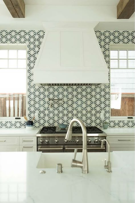 Windows flank a white wood range hood mounted to black and white mosaic wall tiles over a stainless steel oven range positioned between white shaker cabinets topped with a white quartz countertop. Kitchen Oven Between Windows, Range Hood Between Two Windows, Oven Between Two Windows, White Oven Hood, Hood Range Between Windows, White Shaker Hood Range, Oven Hood Between Two Windows, Kitchen Hood Between Windows, Vent Hood Between Windows