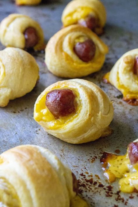 Mini Crescent Dogs are cocktail sized beef smokies wrapped inside cheddar cheese and tender crescent rolls. These crowd-pleasing pigs in a blanket are the perfect party fingerfood and always give you reason to celebrate! | A Wicked Whisk #minicrescentdogs #miniscrescenthotdogs #minicrescentdogspillsbury #minicrescentdogsrecipe #minicrescentdogswithcheese #minipigsinablanket #minipigsinablanketcrescentrolls #minipigsinablanketwithcheese #minipigsinablanketlilsmokies Crescent Roll Mini Hot Dogs, Mini Crescent Dogs, Mini Pigs In A Blanket Crescent Rolls, Mini Hot Dogs In Crescent Rolls, Smokies Wrapped In Crescent Rolls, Brunch Tailgate, Egg Muffin Cups Healthy, Hot Dog Crescent Rolls, Crescent Dogs